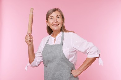 Photo of Happy woman with rolling pin on pink background