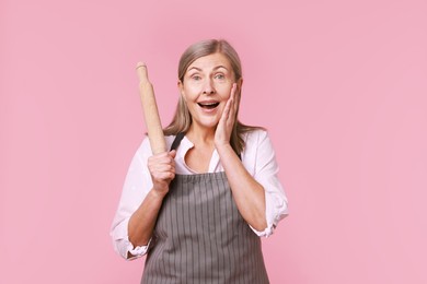 Photo of Emotional woman with rolling pin on pink background