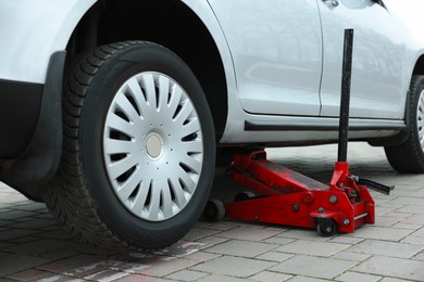 Photo of Car lifted by scissor jack on roadside outdoors