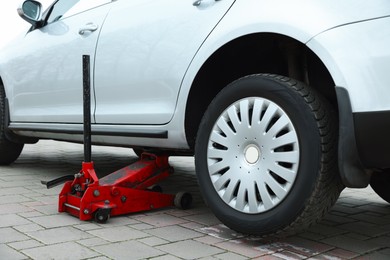 Photo of Car lifted by scissor jack on roadside outdoors