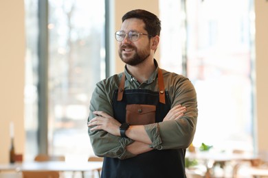 Photo of Smiling business owner with crossed arms in his cafe