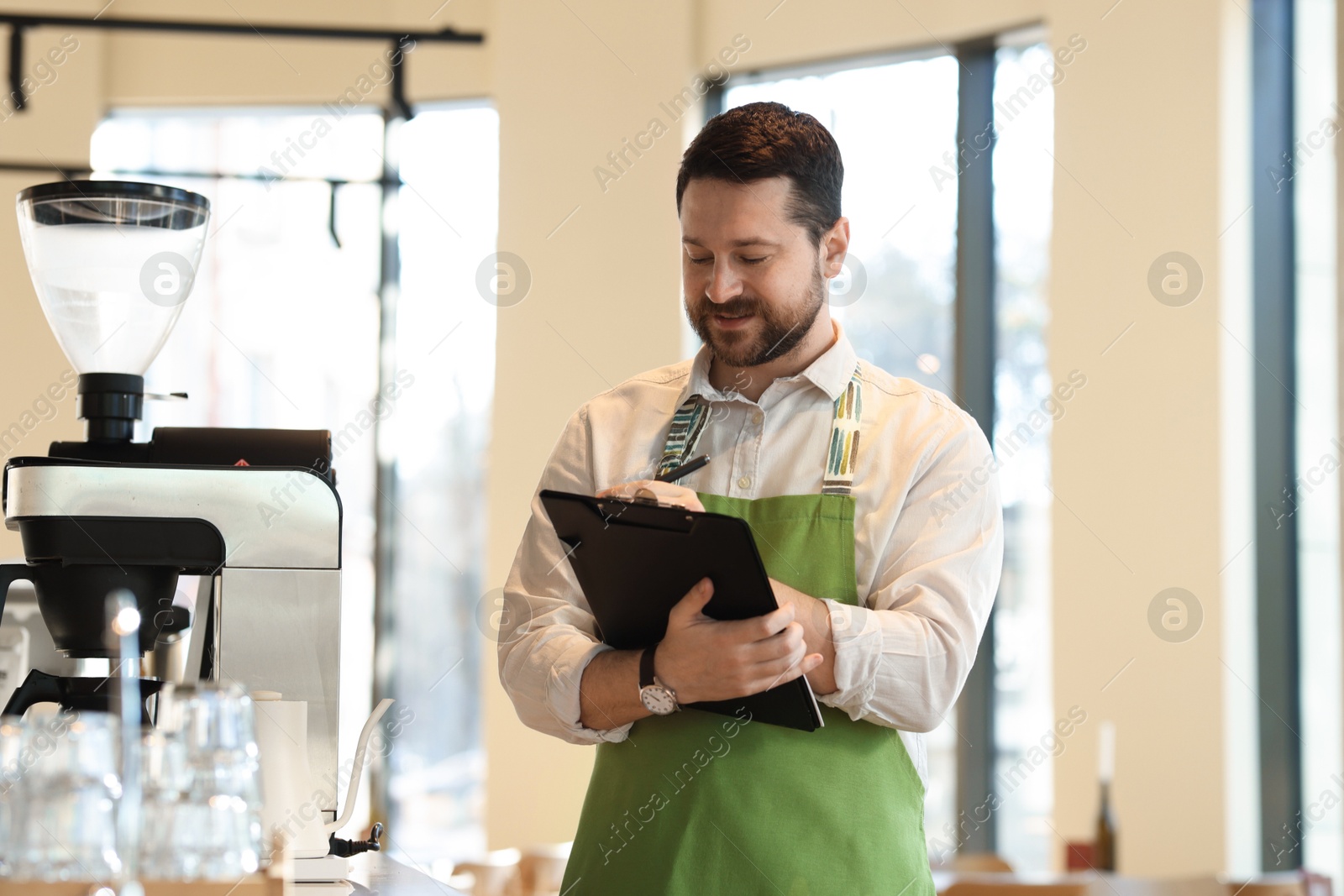 Photo of Handsome business owner working with clipboard in his cafe