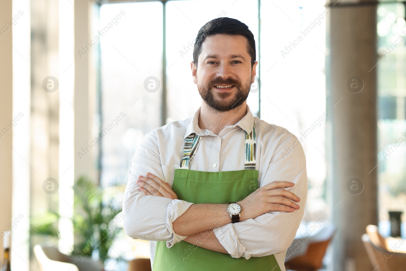 Photo of Portrait of smiling business owner with crossed arms in his cafe