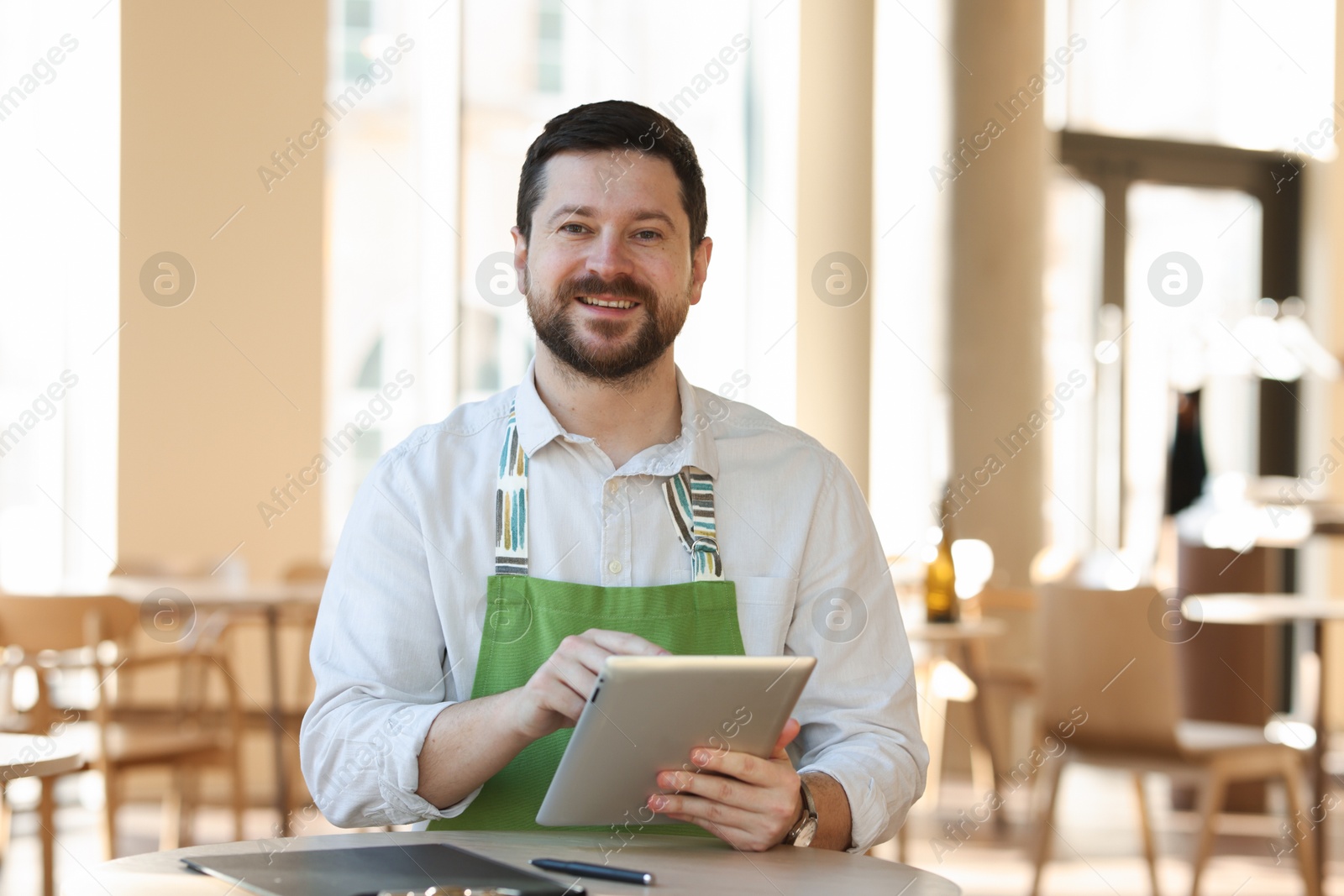 Photo of Smiling business owner with tablet in his cafe