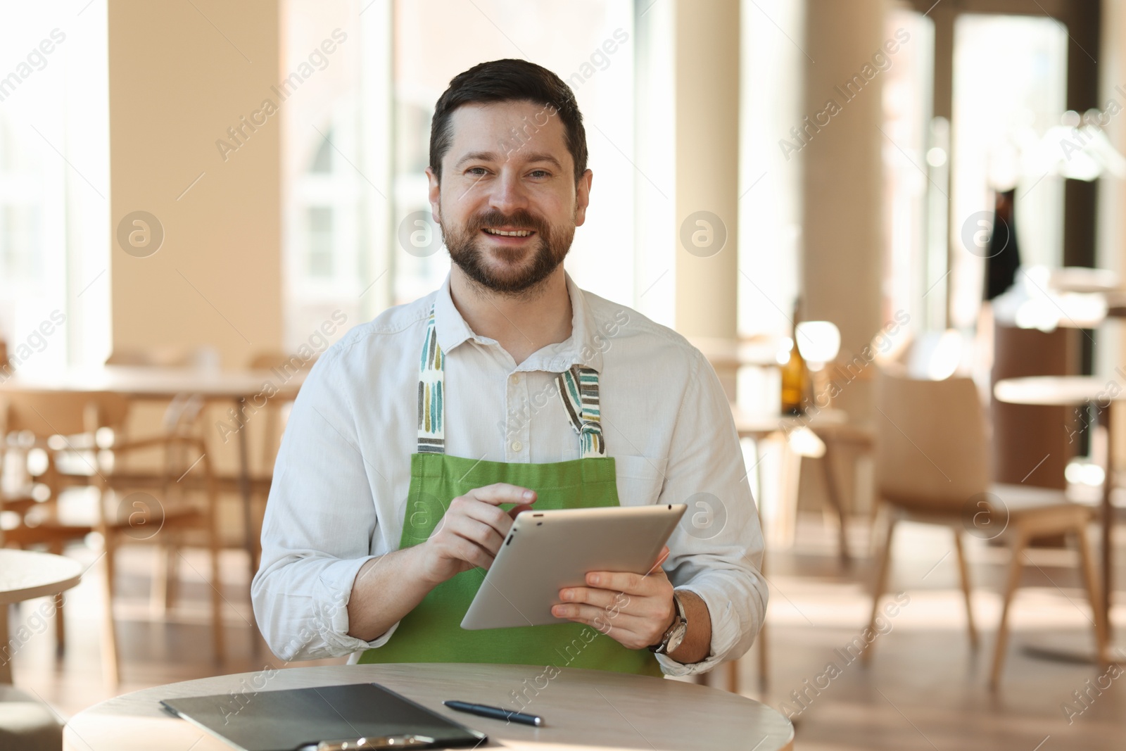 Photo of Smiling business owner with tablet in his cafe