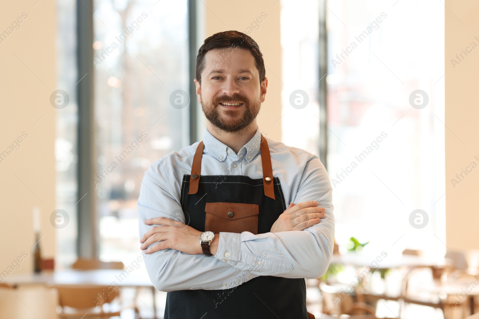 Photo of Portrait of smiling business owner with crossed arms in his cafe