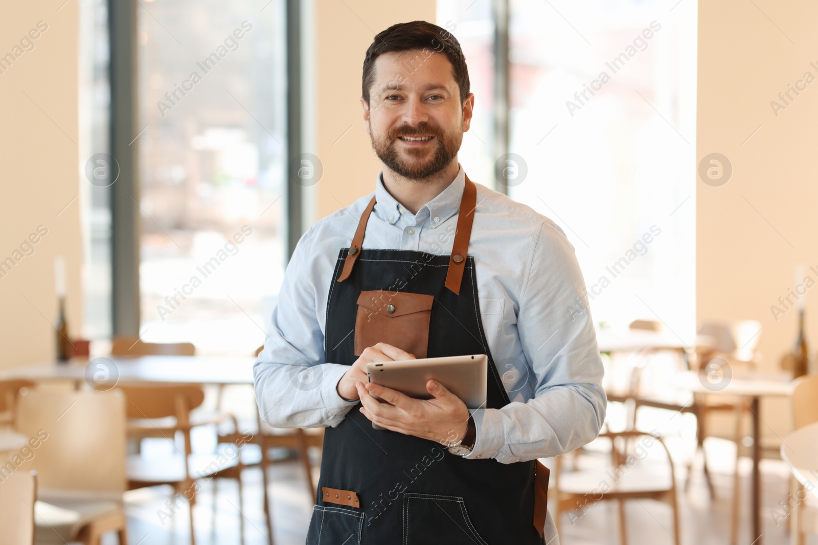 Photo of Portrait of smiling business owner with tablet in his cafe