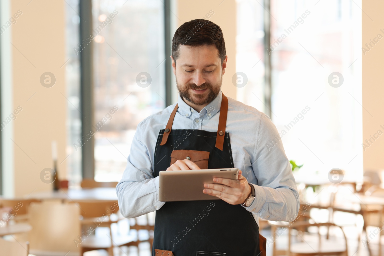 Photo of Handsome business owner working with tablet in his cafe