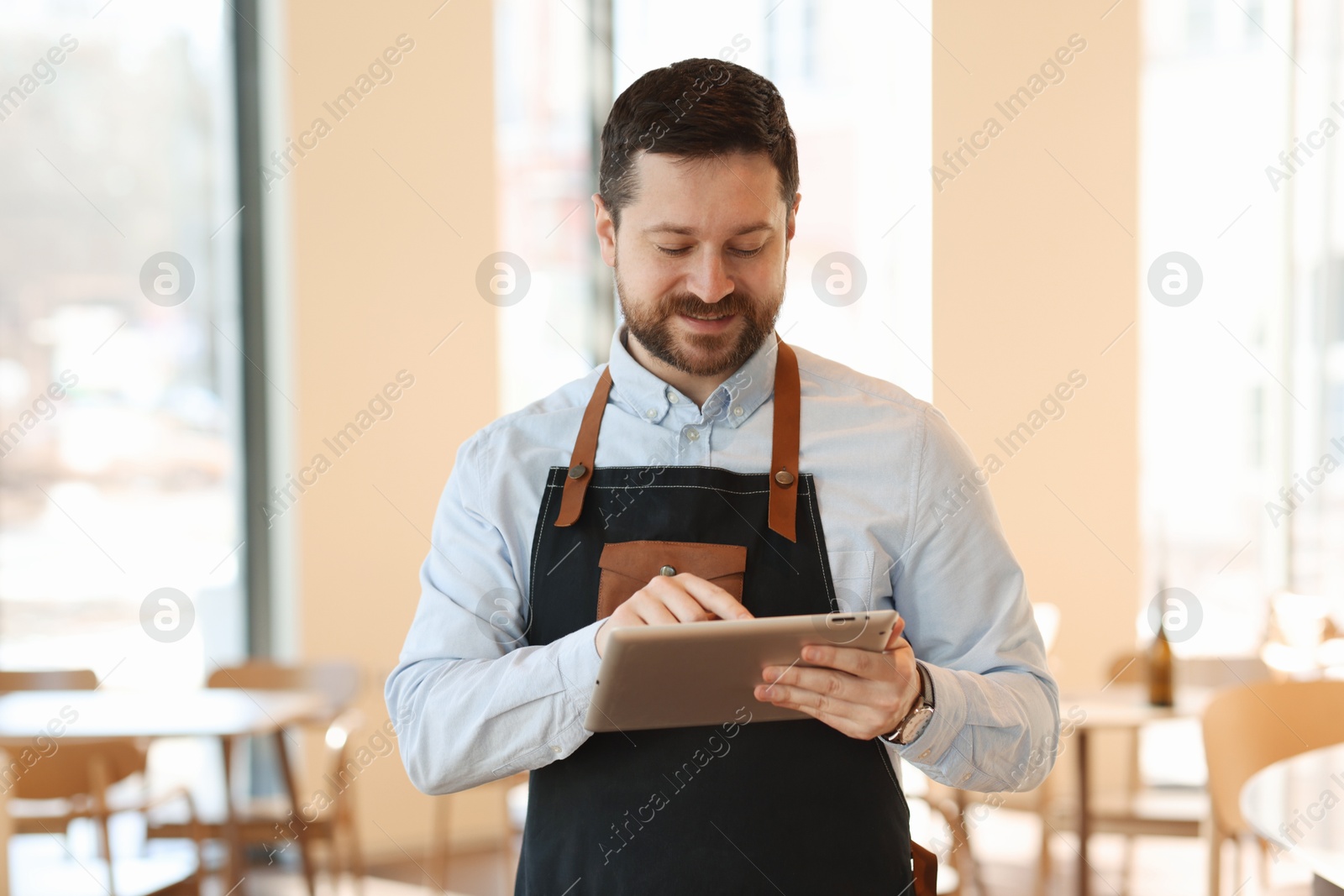 Photo of Handsome business owner working with tablet in his cafe