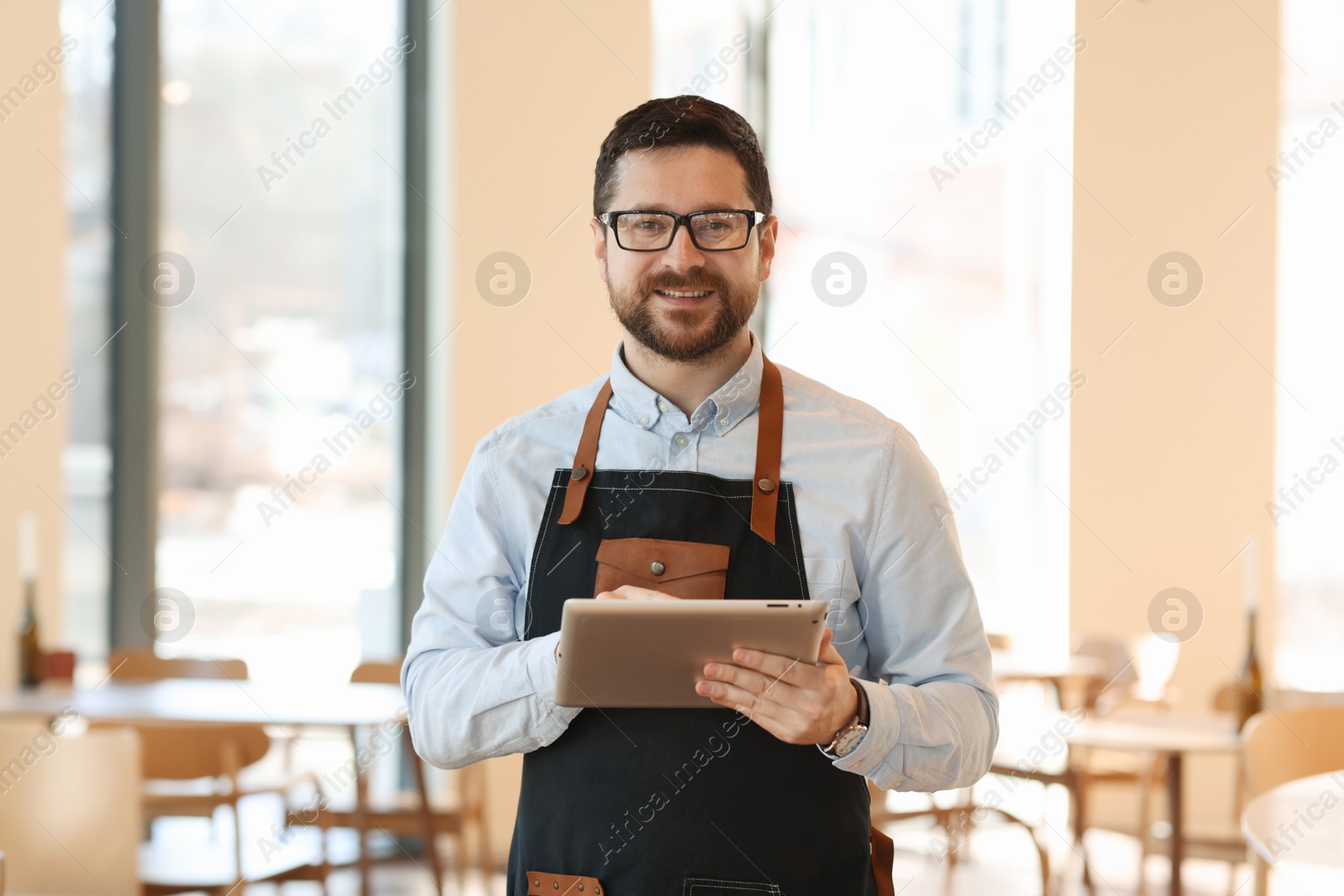 Photo of Portrait of smiling business owner with tablet in his cafe