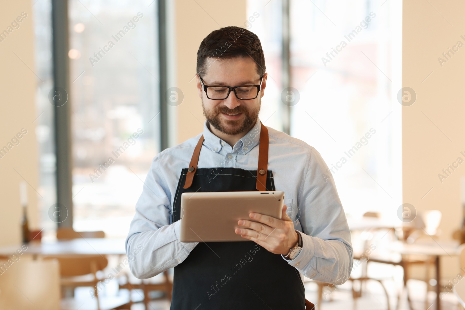 Photo of Portrait of smiling business owner with tablet in his cafe