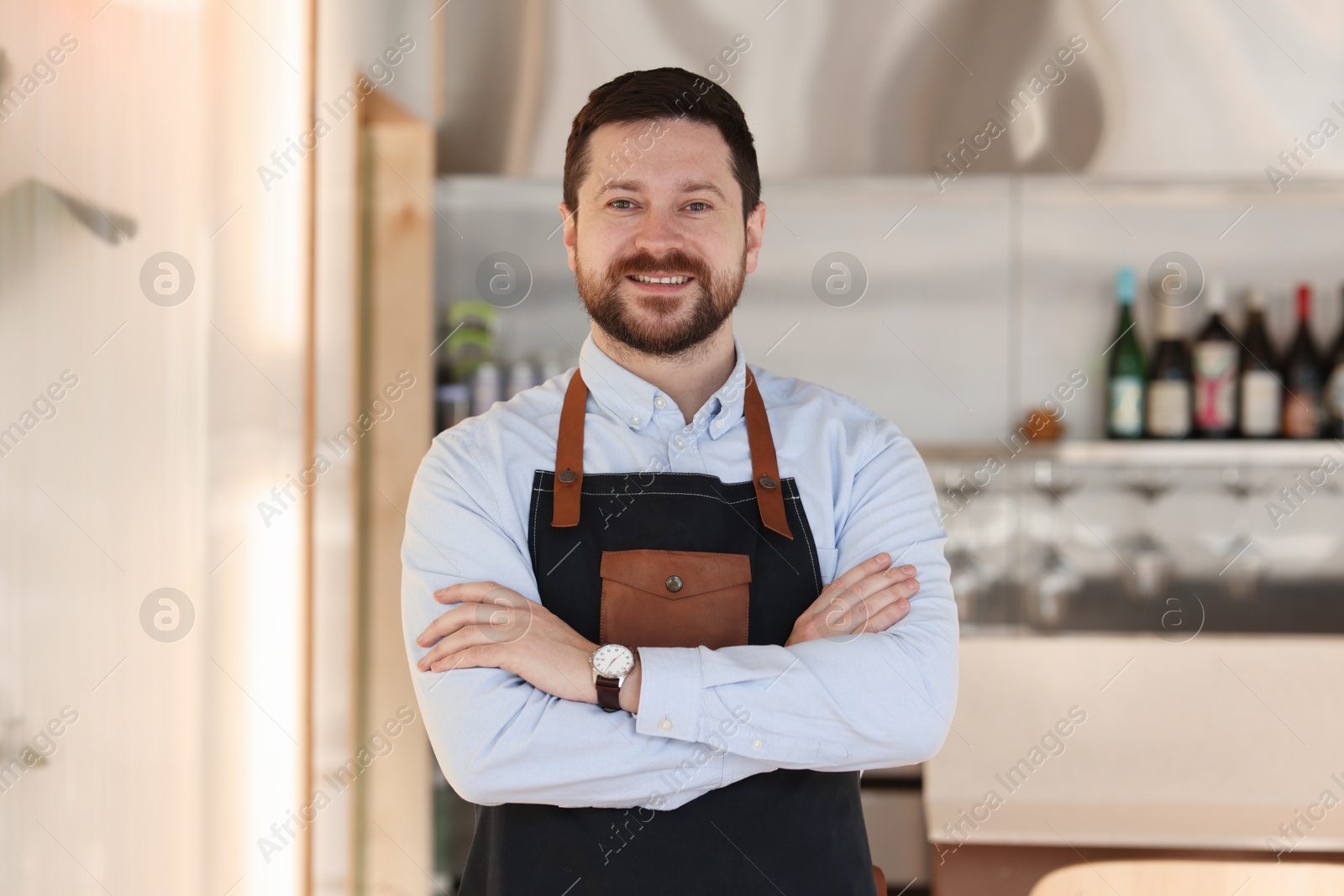 Photo of Portrait of smiling business owner with crossed arms in his cafe