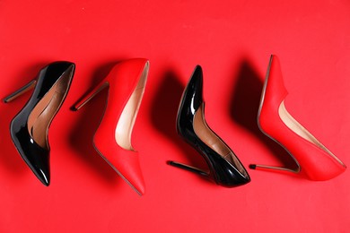 Photo of High heeled shoes on crimson background, flat lay