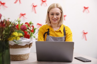 Photo of Business owner working on laptop at table in her flower shop