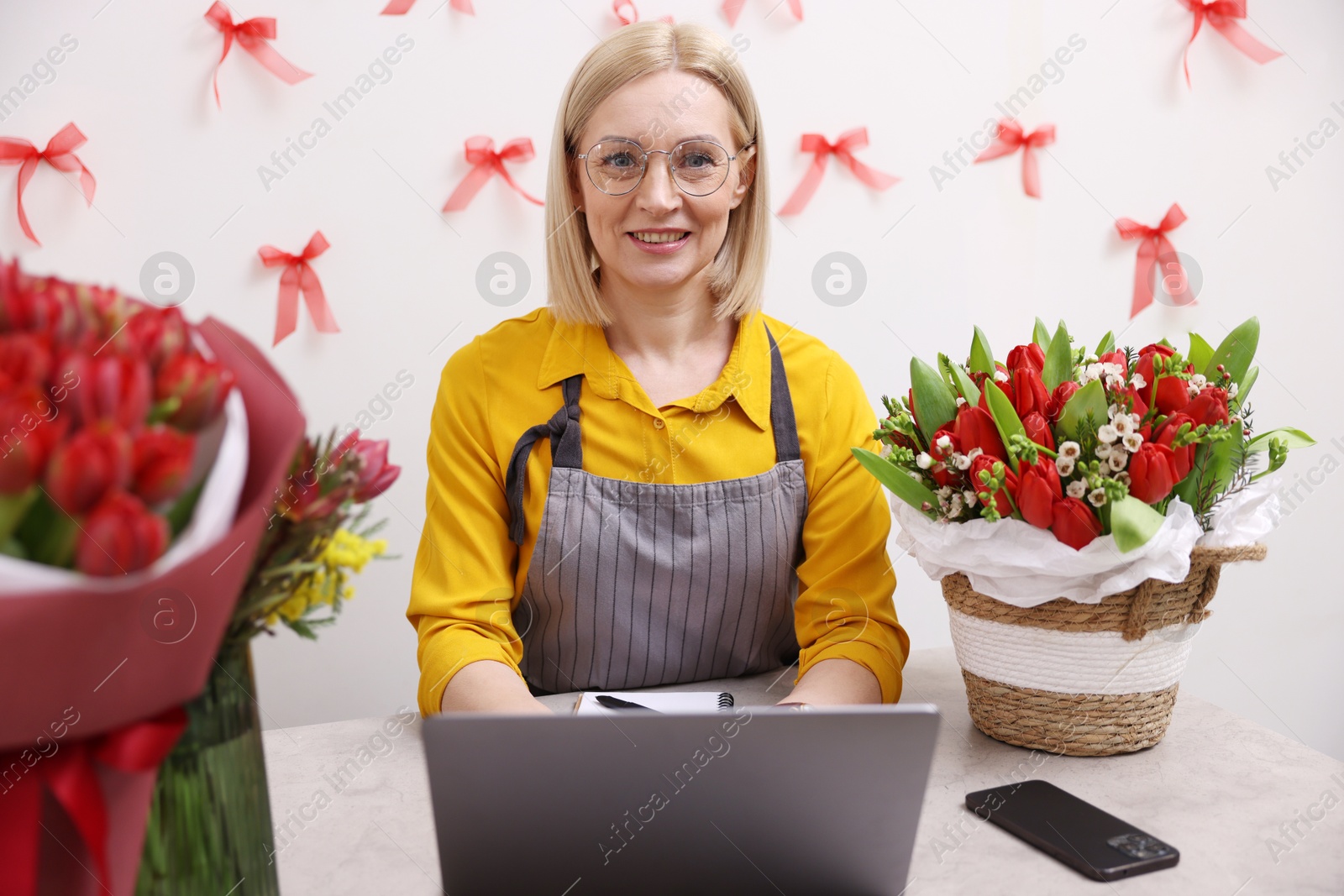 Photo of Business owner working on laptop at table in her flower shop