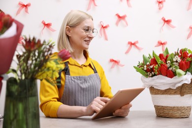 Photo of Business owner with tablet at table in her flower shop