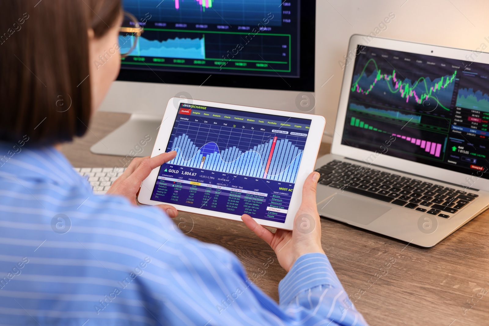 Photo of Stock exchange. Woman analysing financial market on tablet at wooden table indoors