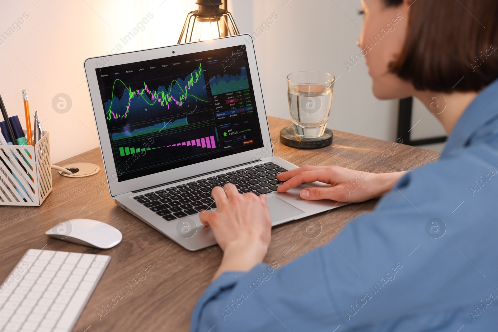 Photo of Stock exchange. Woman analysing financial market on laptop at wooden table indoors, closeup