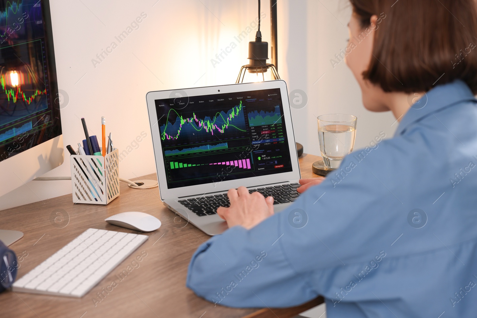 Photo of Stock exchange. Woman analysing financial market on laptop at wooden table indoors