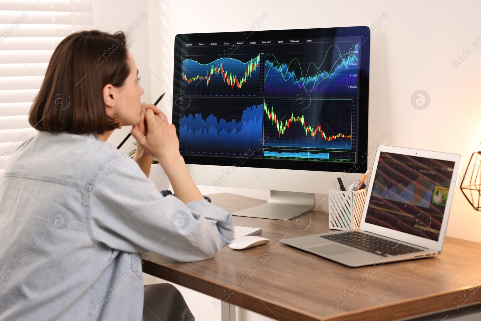 Photo of Stock exchange. Woman analysing financial market on computer at wooden table indoors