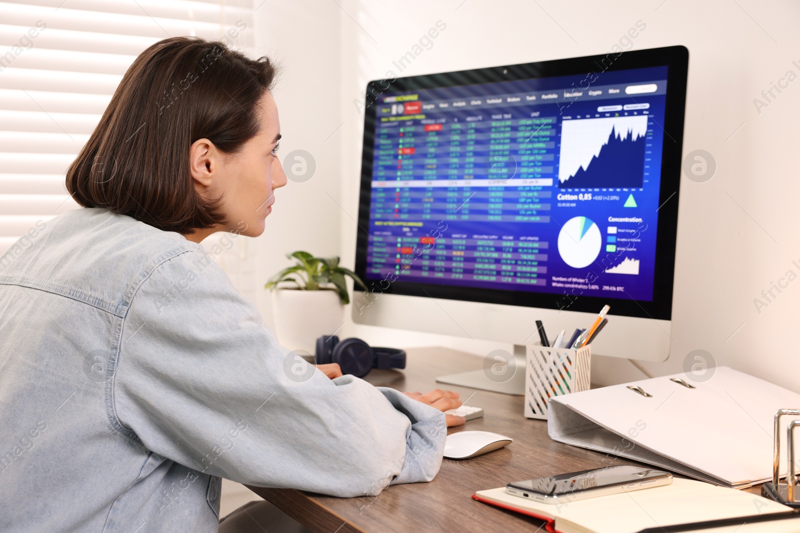 Photo of Stock exchange. Woman analysing financial market on computer at wooden table indoors