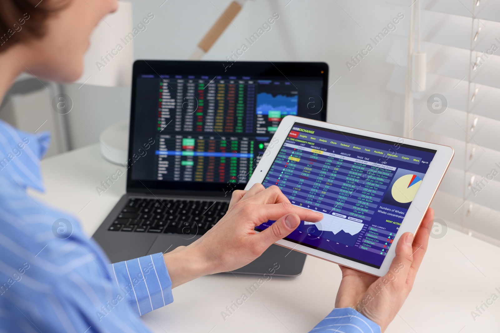 Photo of Stock exchange. Woman analysing financial market on tablet at white table indoors, closeup