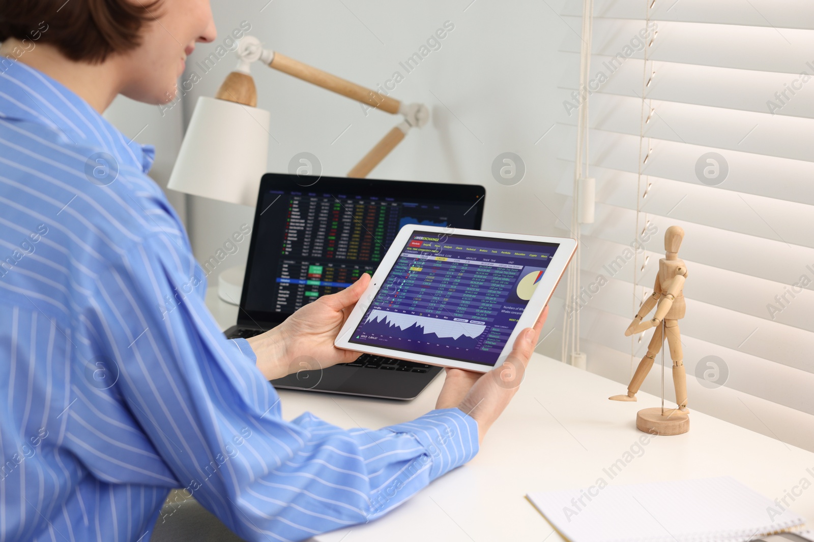 Photo of Stock exchange. Woman analysing financial market on tablet at white table indoors, closeup