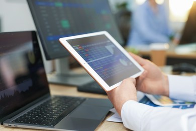 Photo of Stock exchange. Man working at desk in office, closeup