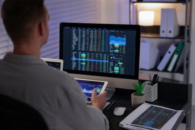 Photo of Stock exchange. Man working in office at night, back view