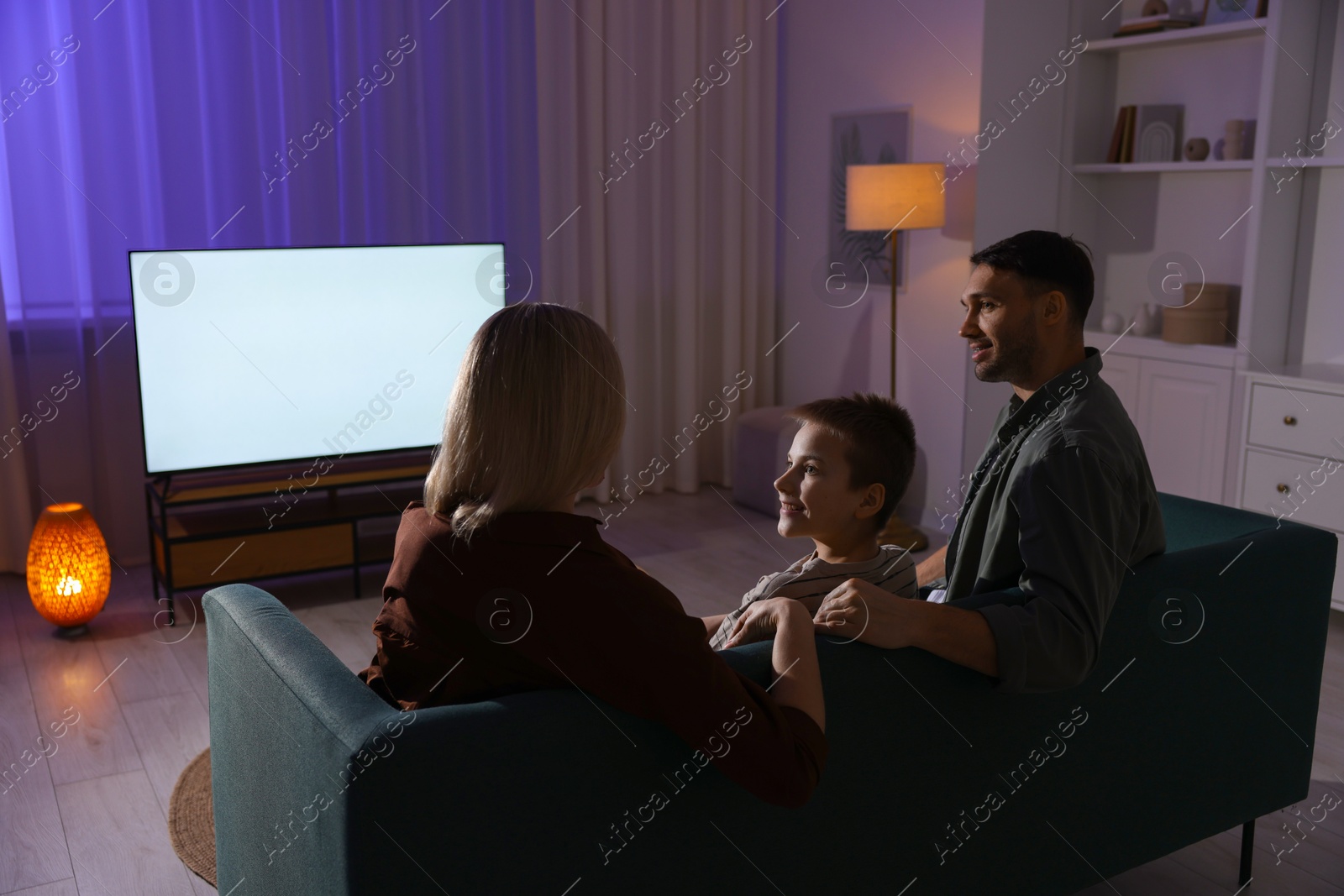 Photo of Happy family watching tv together at home in evening