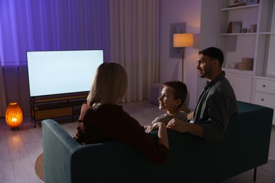 Photo of Happy family watching tv together at home in evening