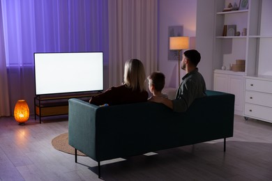 Photo of Happy family watching tv together at home in evening