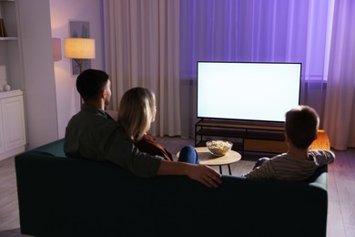 Photo of Happy family watching tv together at home in evening