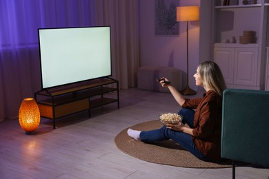 Photo of Woman with popcorn watching tv at home in evening