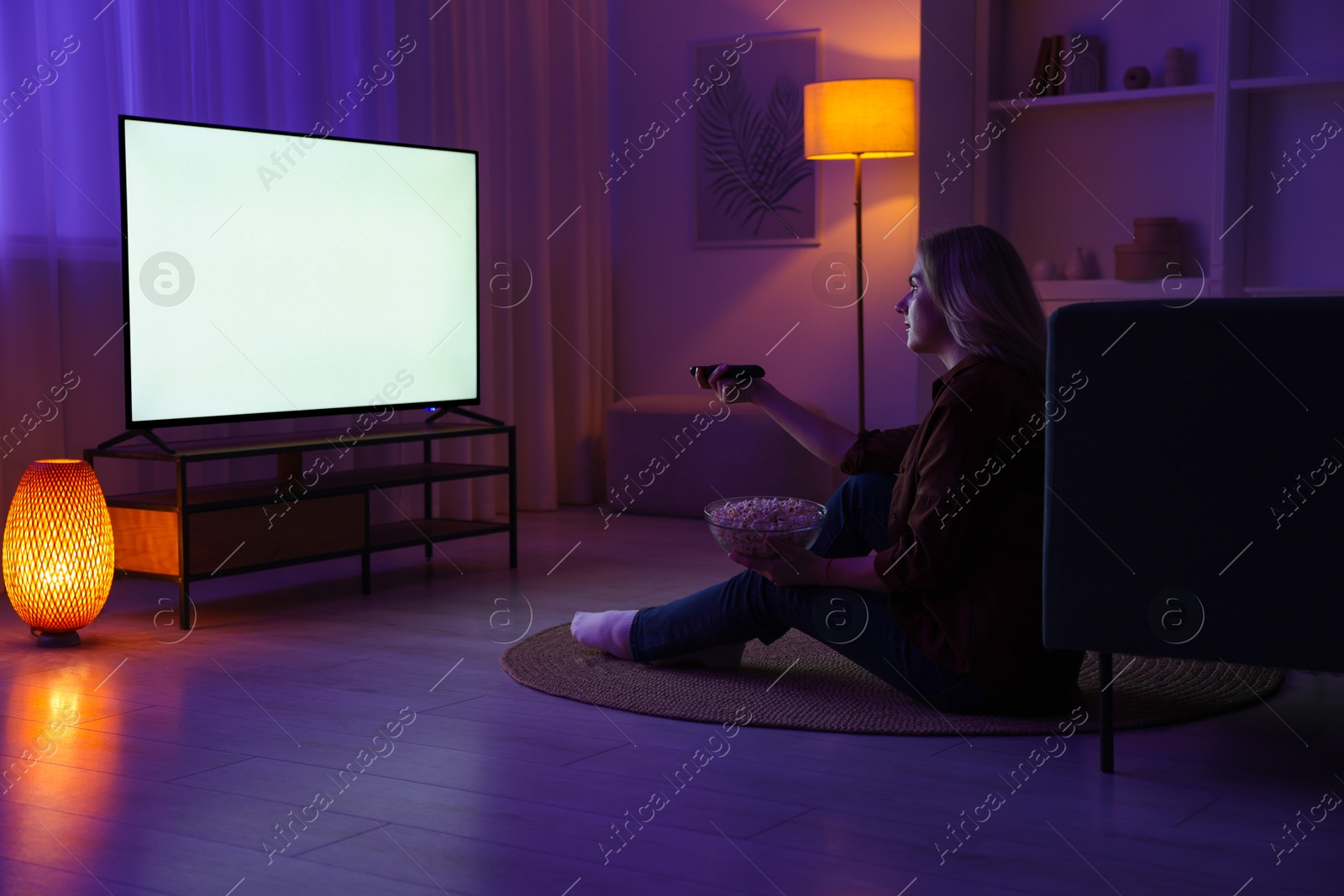 Photo of Woman with popcorn watching tv at home in evening