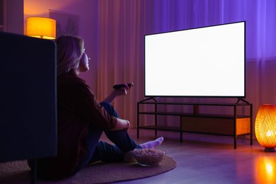 Photo of Woman with popcorn watching tv at home in evening