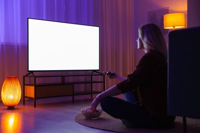 Photo of Woman with popcorn watching tv at home in evening