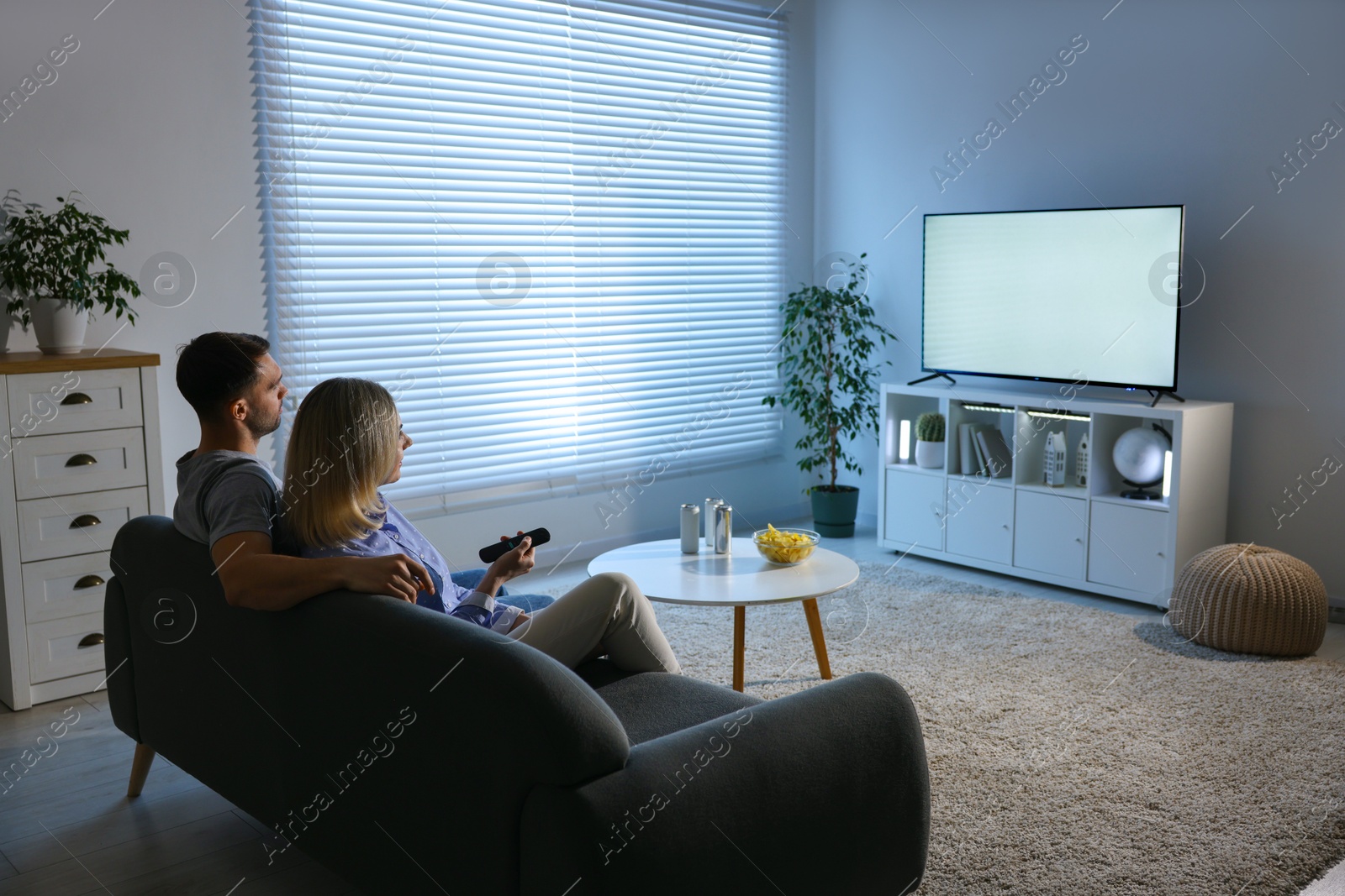 Photo of Lovely couple watching tv on couch at home