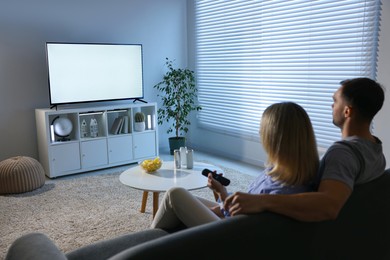 Photo of Lovely couple watching tv on couch at home, back view