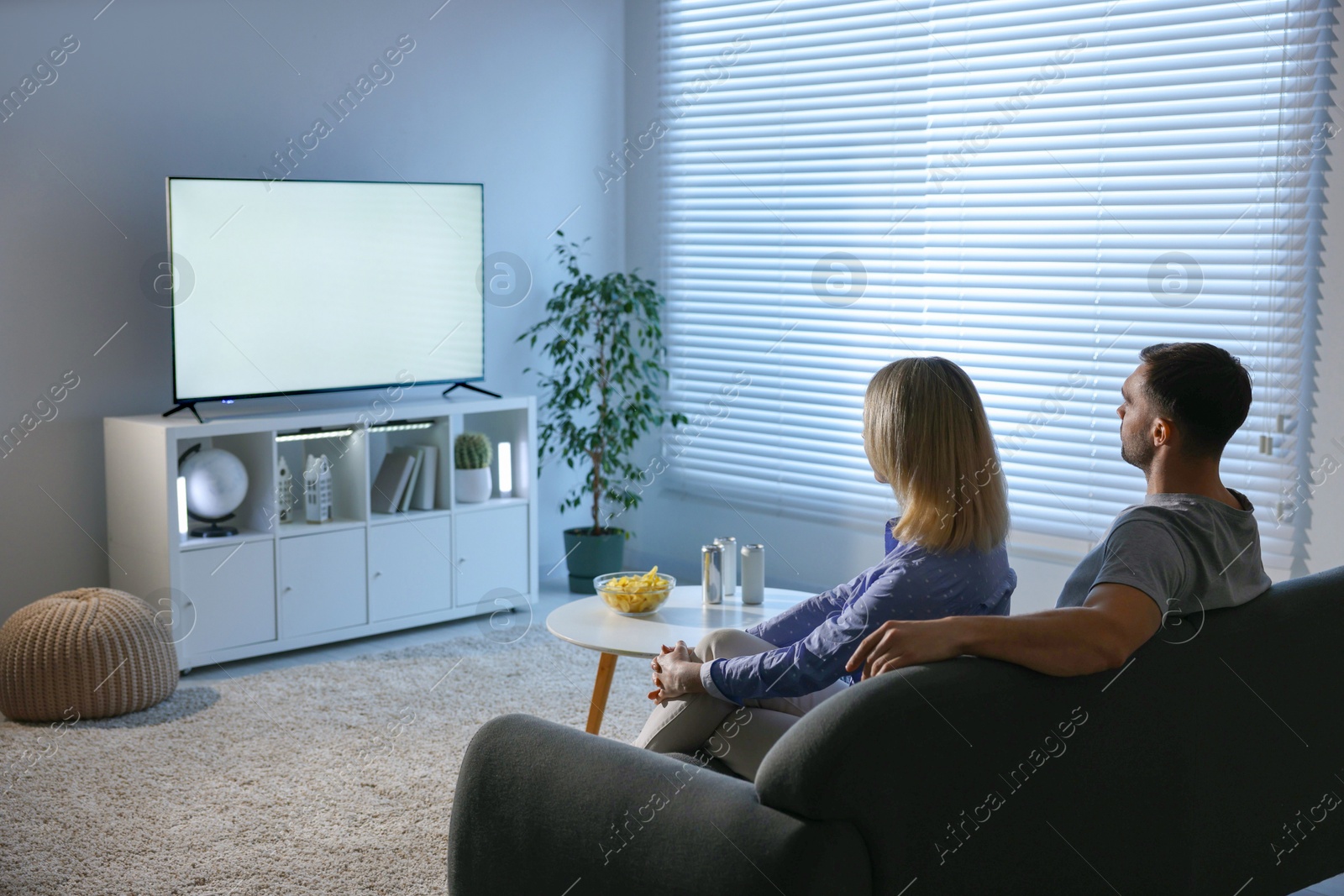 Photo of Lovely couple watching tv on couch at home