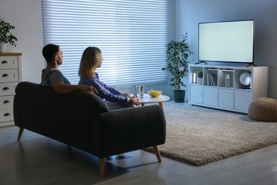 Photo of Lovely couple watching tv on couch at home