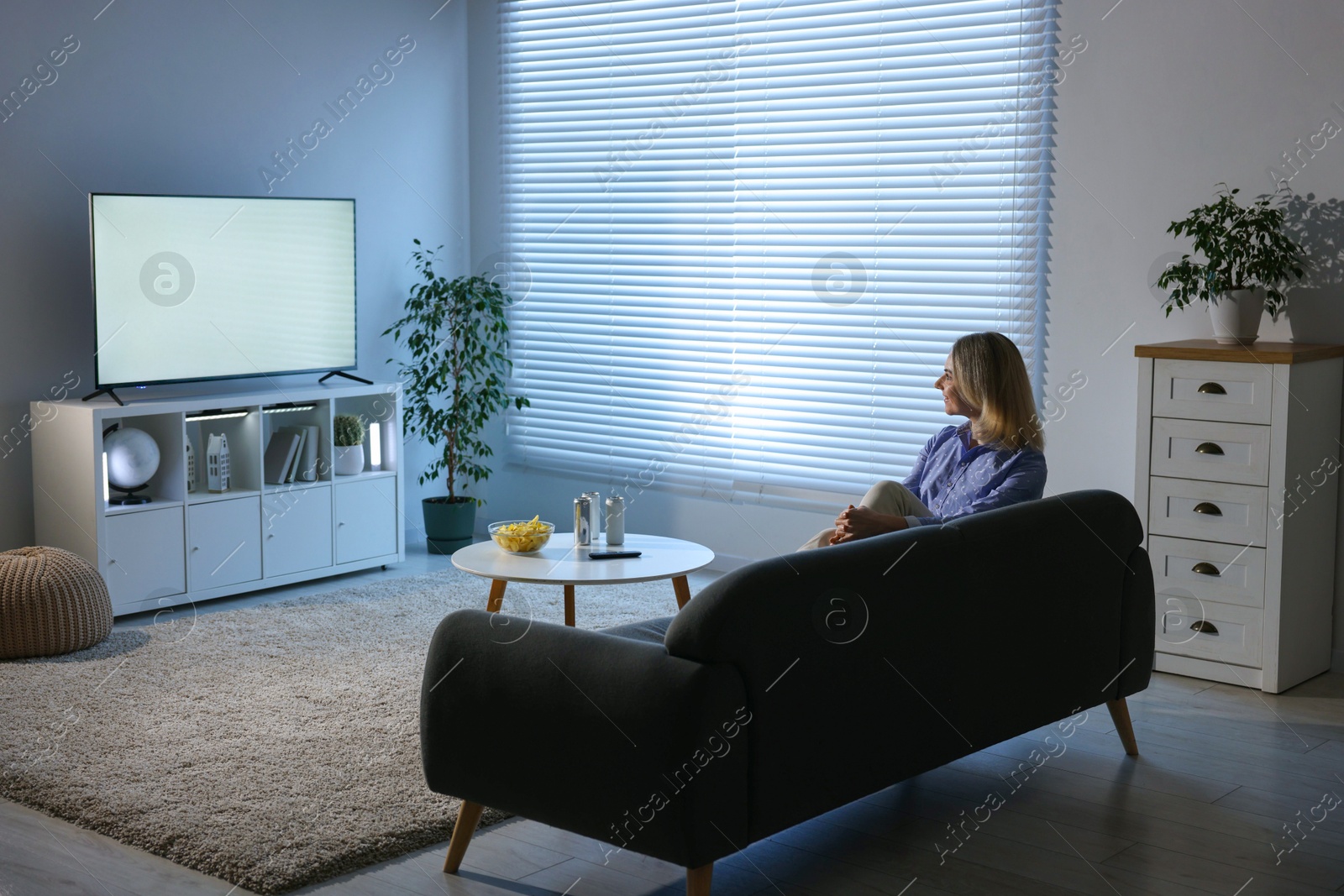 Photo of Woman watching tv on couch at home