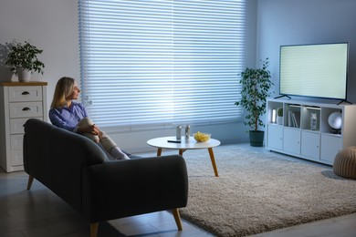 Photo of Woman watching tv on couch at home