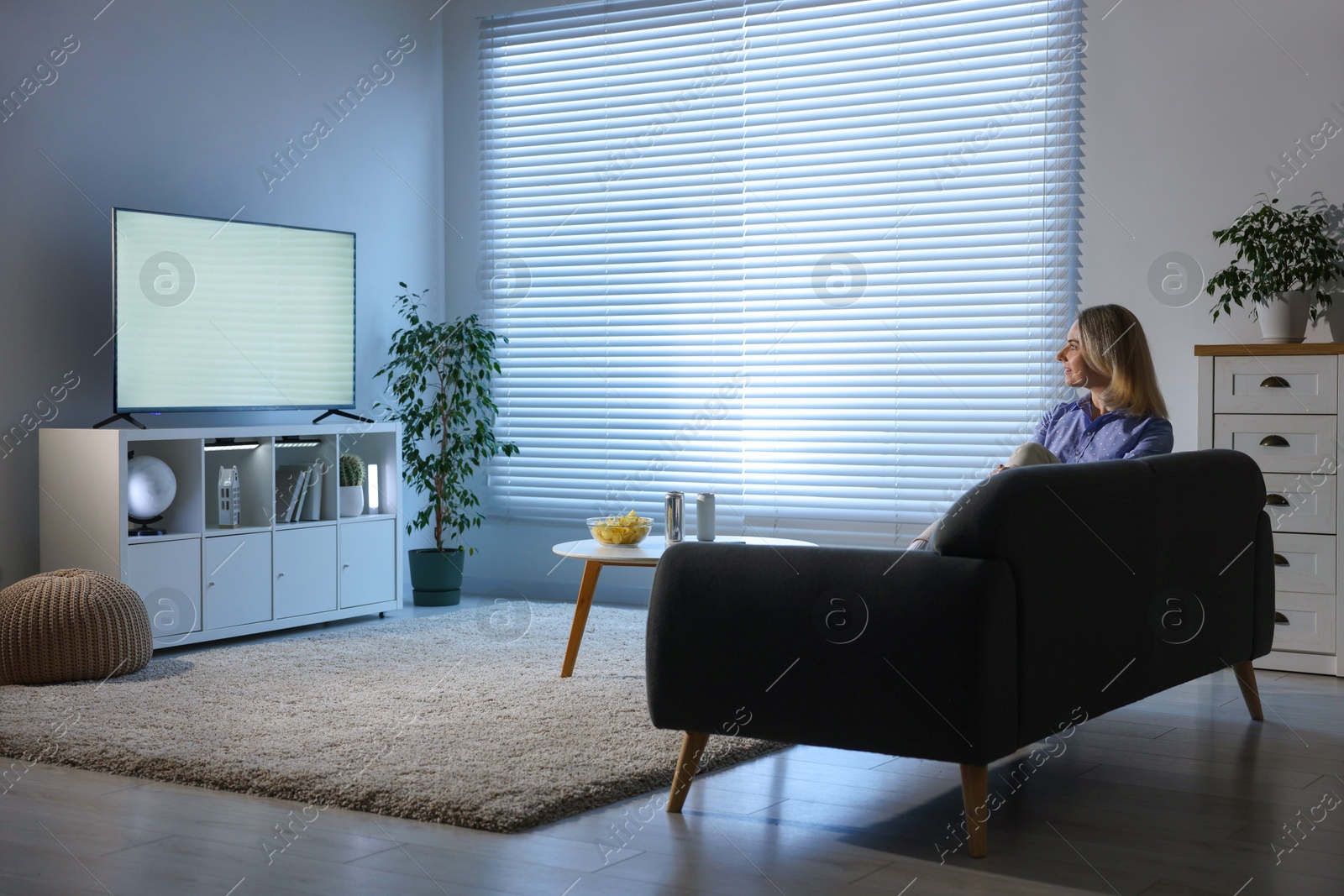 Photo of Woman watching tv on couch at home