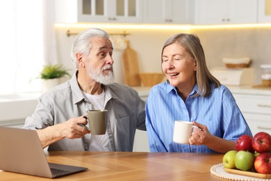 Photo of Cute elderly couple laughing at table in kitchen