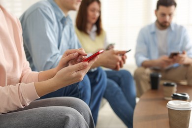 Photo of Internet addiction. Group of people with smartphones and coffee at table indoors, closeup