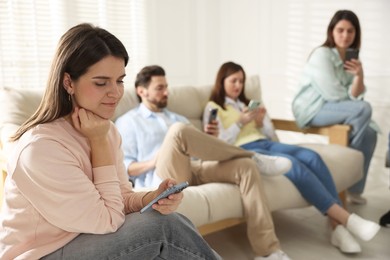 Photo of Internet addiction. Group of people with smartphones on sofa indoors, selective focus