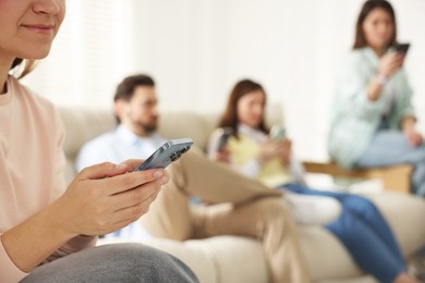 Photo of Internet addiction. Group of people with smartphones on sofa indoors, selective focus