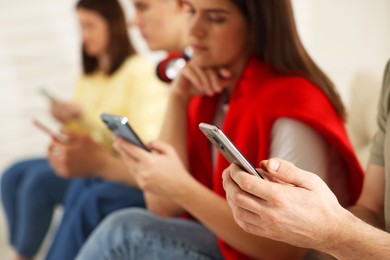 Photo of Internet addiction. Group of people with smartphones indoors, closeup