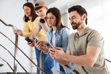 Photo of Internet addiction. Group of people with smartphones on stairs indoors